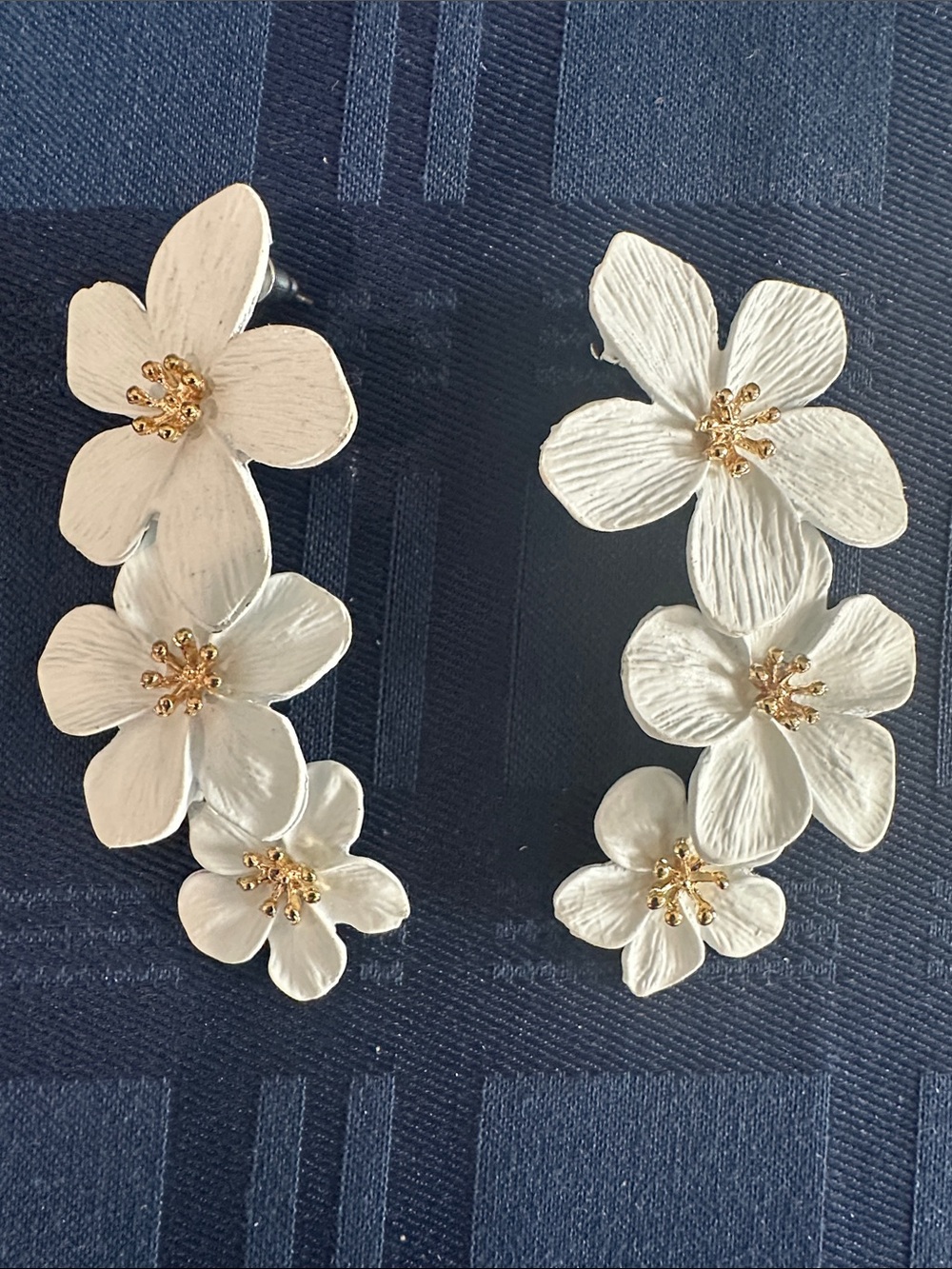 A pair of white tiered flower statement drop earrings featuring textured petal